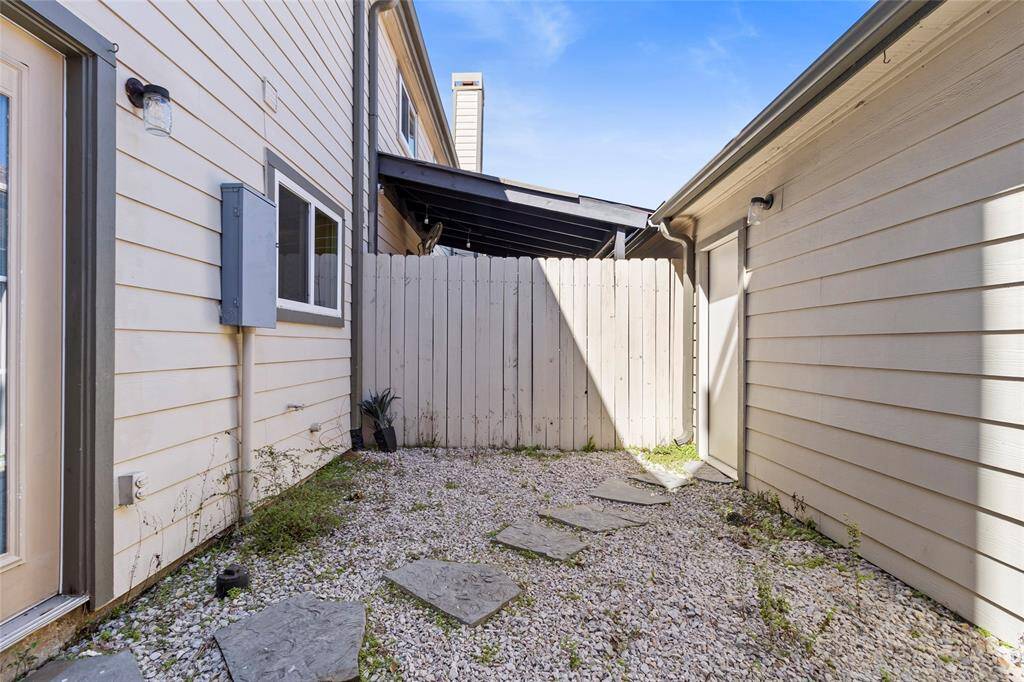 This photo shows your small, enclosed courtyard, featuring gravel and stepping stones on the ground, with a wooden fence at the end. It’s a low-maintenance outdoor space with plenty of potential for gardening or creating a cozy seating area.