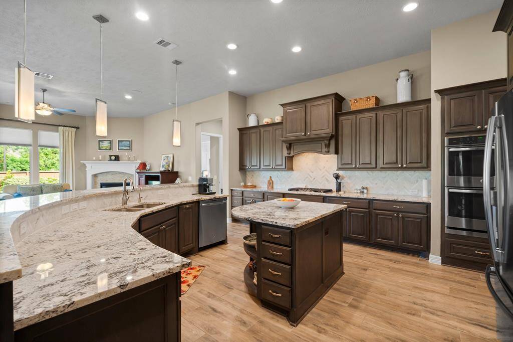 A pristine showcase of elegance and function, this extraordinary kitchen features stainless steel appliances, including a 5-burner cooktop with furniture-quality wood vent hood, double convection ovens, microwave, and dishwasher with third rack. Designed for both gourmet cooking and sophisticated entertaining, this kitchen is truly the heart of the home.