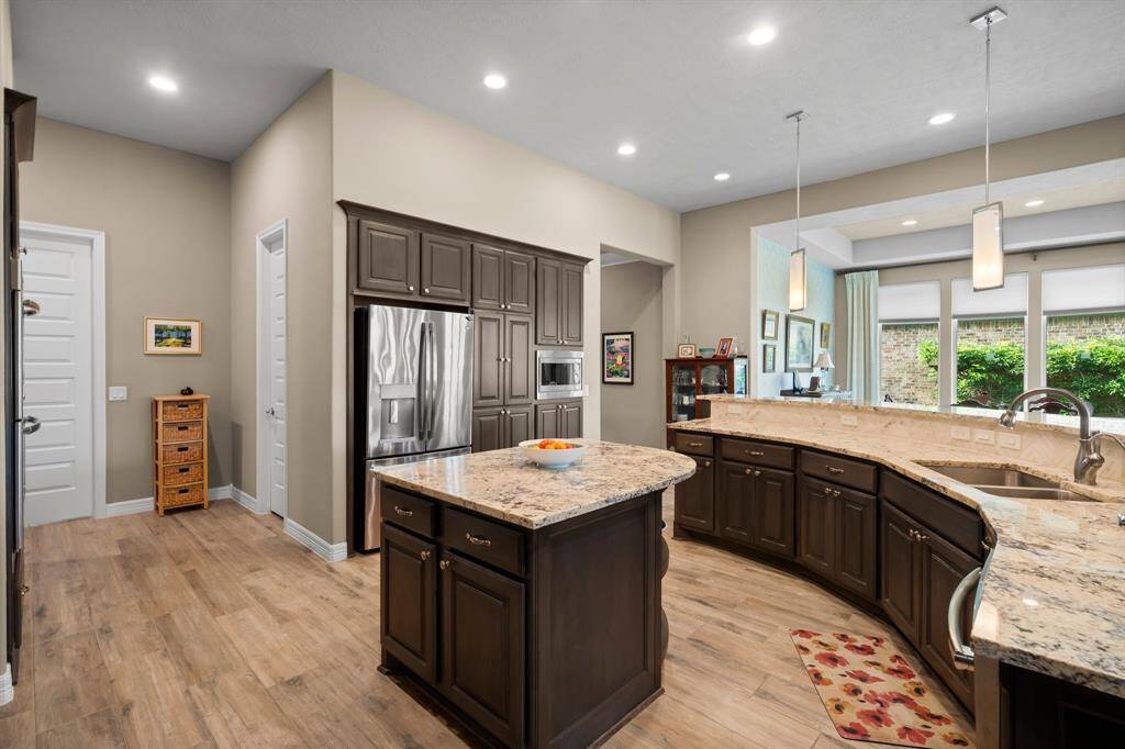 This kitchen is a striking showcase of modern elegance and everyday functionality. Rich wood cabinetry offers abundant storage, complemented by sleek granite countertops.  The large sink—complete with a pull-out sprayer and built-in filtered water dispenser—adds convenience and style. Designed to impress, this chef’s kitchen effortlessly accommodates both daily living and grand-scale entertaining.