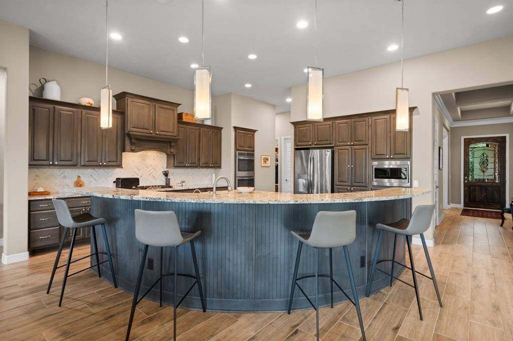 This versatile peninsula highlights a curved bead board knee wall, sleek pendant lighting, extra cabinetry for organization, and breakfast bar seating for six.