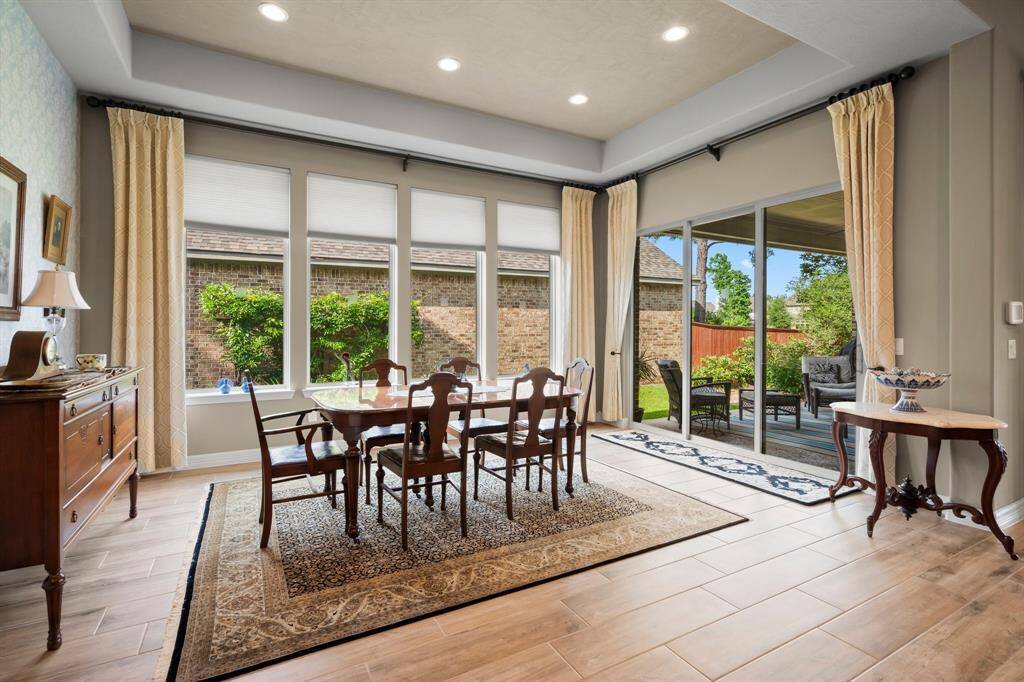 Experience refined dining or casual breakfasts in this elegant Formal Dining Room, where walls of windows frame serene views of the covered porch and sparkling pool, creating a breathtaking backdrop for any occasion. Whether hosting a sophisticated dinner party or enjoying an intimate meal, this space exudes timeless luxury. A sliding glass door offers seamless access to the outdoor living area, perfectly blending indoor comfort with alfresco entertaining.