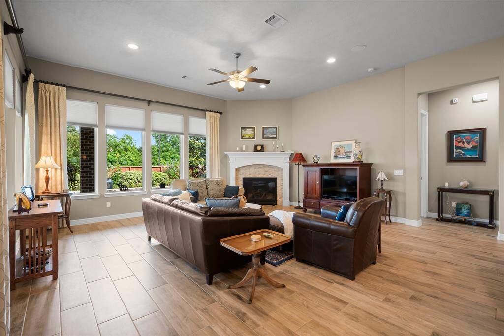 The heart of this inviting Family Room is the stacked-stone corner fireplace with a convenient gas starter and gas logs, offering both warmth and style. Designed for both function and comfort, this room also features wood-look tile flooring, recessed lighting, pleated easy pull-down shades, surround sound speakers, and lighted ceiling fan.