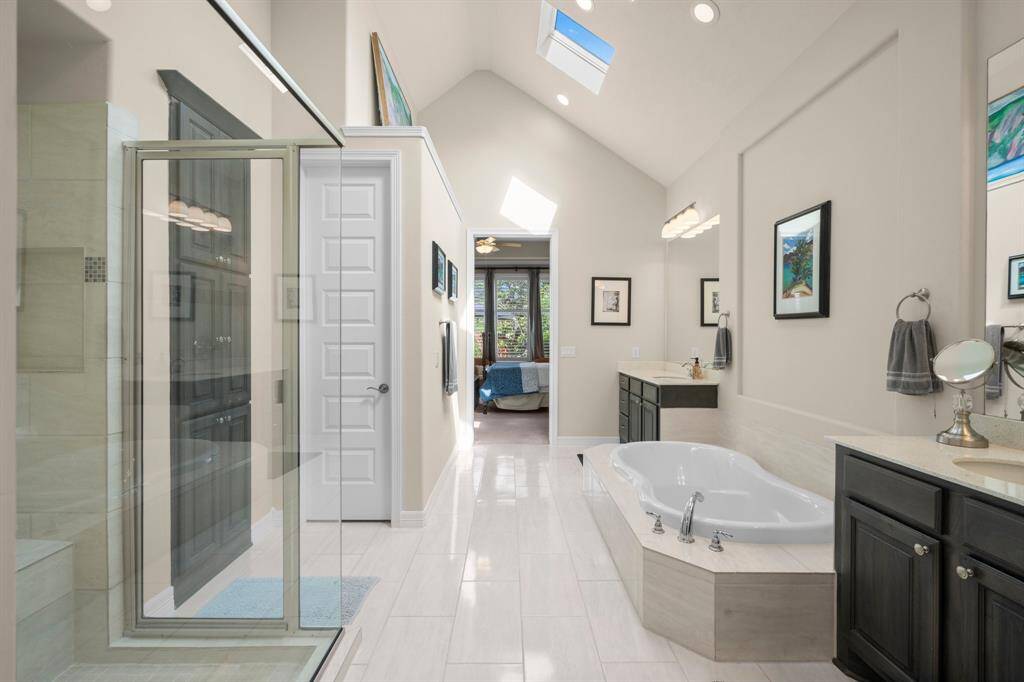 Truly a retreat for getting ready on a busy morning or stealing away for an evening out, your en-suite bath features double door entry, rectangular tile flooring, three skylights, dual vanities, large shower, deep soaking tub, linen cabinet, recessed lighting, private commode, and large walk-in closet with built-in shelving and full-length mirror.