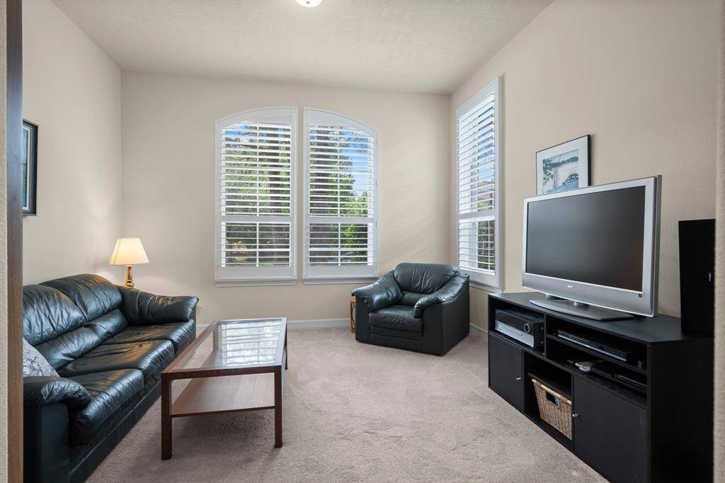 Two additional downstairs bedrooms are thoughtfully positioned in a private wing of the home, each featuring its own en-suite bath for ultimate comfort and convenience. This particular bedroom offers plush carpeting underfoot, three sun-filled windows with plantation shutters, a walk-in closet, and a ceiling light—creating a serene and comfortable retreat for guests or family members.
