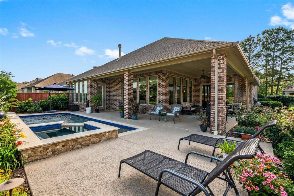 Before you even step inside, you'll be captivated by the stunning backyard oasis. An expansive wrap-around covered porch with elegant Kool-Deck flooring sets the stage for outdoor luxury. The centerpiece is a beautifully designed pool and spa, complete with cascading waterfalls and a striking stacked-stone wall—perfect for both relaxation and impressive entertaining.