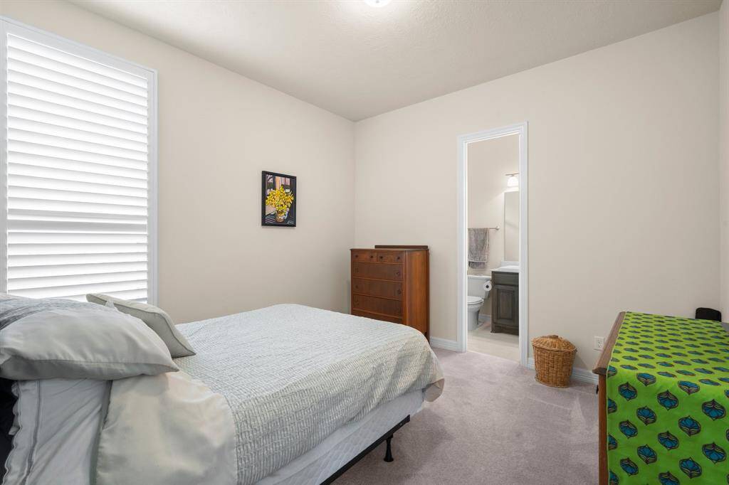 Another secondary bedroom offers lush carpeting, large walk-in closet, sunny window with plantation shutters, and ceiling light. It also has direct access to its own private en-suite bath.