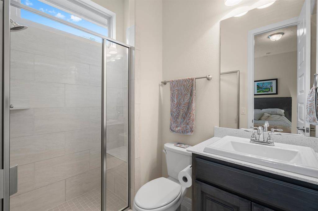 The en-suite bathroom for Bedroom 3 includes single sink with granite countertop, rectangular tile flooring, hall linen closet, toilet, and tiled shower with bench seat, toiletry shelf, and clerestory window.