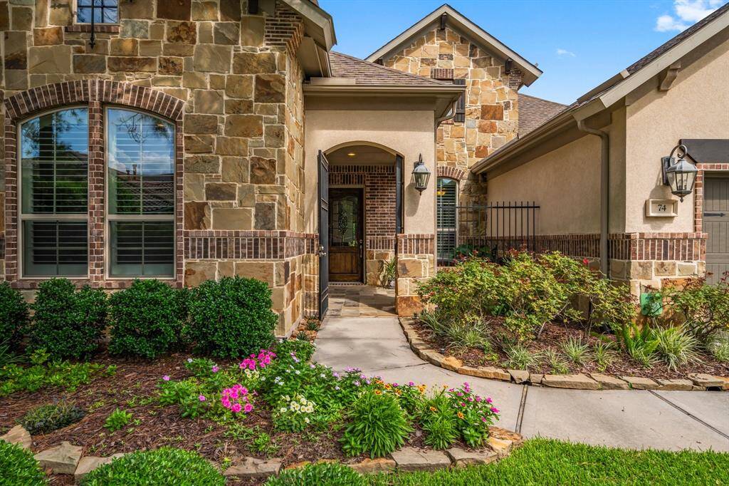 The home’s captivating curb appeal is immediately apparent upon arrival. Detailed brickwork highlights the stone facade. Impeccably manicured landscaping guides you through a wrought-iron gate into a charming front courtyard, elegantly finished with tile flooring.