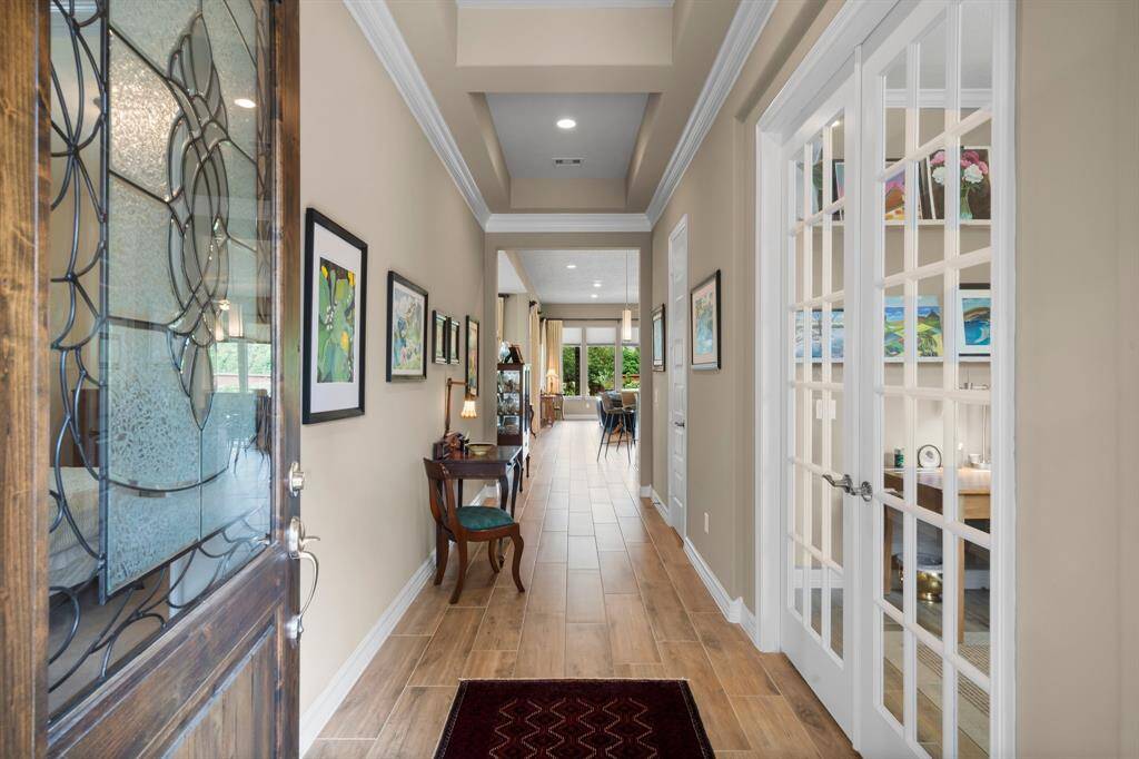 Step into a foyer that exudes warmth and sophistication, where every detail has been thoughtfully designed. Stunning wood-look tile flooring, elegant double crown molding, and a soaring tray ceiling make a grand first impression, while open sightlines effortlessly guide the eye toward the living space and the backyard beyond. There is plenty of space for an entry table or bench.