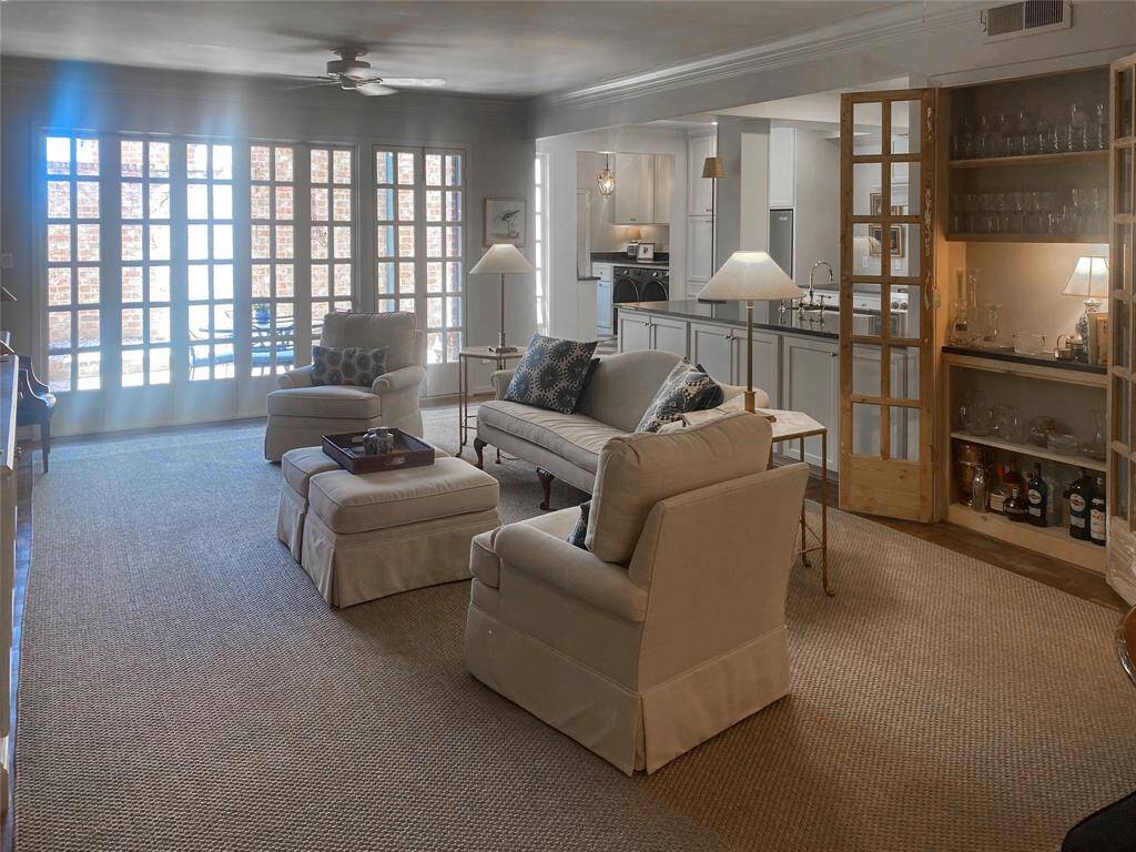 This photo of the family room, beautifully filtered from morning light, was taken from the foyer and shows the open concept of the adjacent breakfast room and kitchen. Double doors lead to the brick-walled back patio.