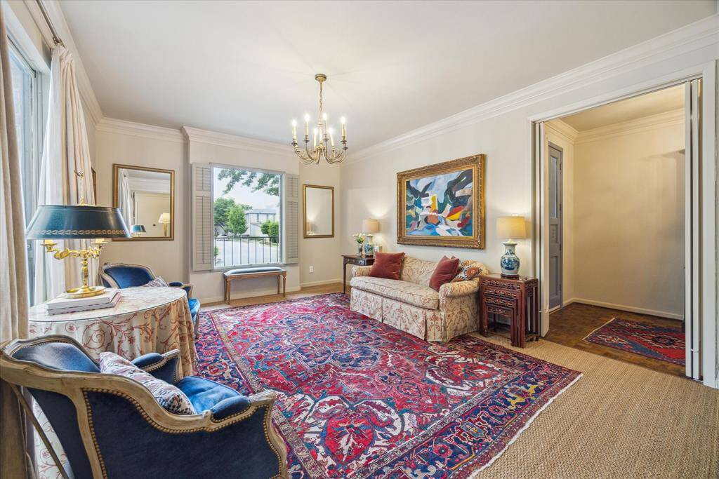 The formal living room boasts a lovely brass chandelier, crown molding and seagrass carpeting and enjoys views of the front lawn. This room could also be used as a beautiful private study.