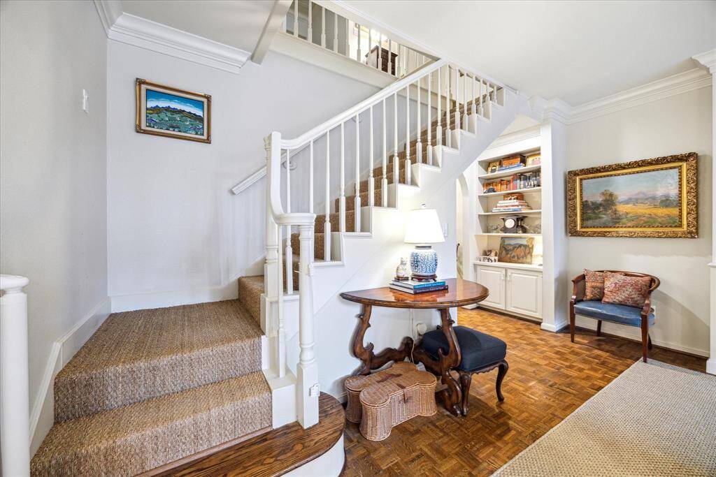 This view of the staircase highlights the seagrass flooring and built-in bookcase, with the entryway just beyond.