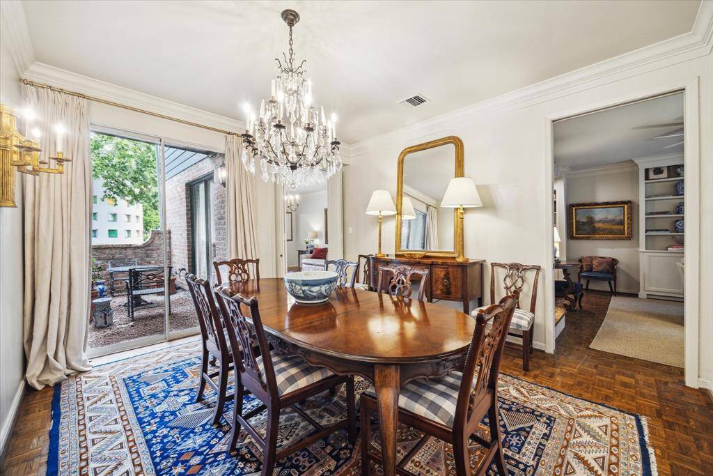 The formal dining room enjoys access to one of the multiple patios that also connects to the formal living room/study just beyond. Note the stunning crystal chandelier, decorative crown molding and parquet wood floors.