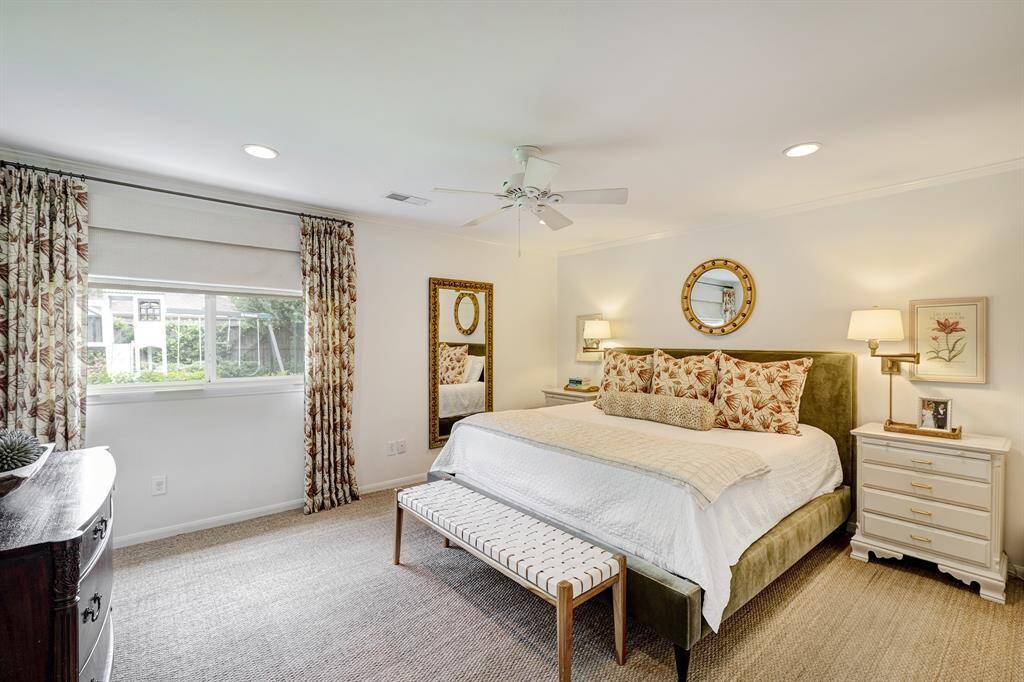 Spacious and serene primary suite with neutral tones, ceiling fan, and elegant crown molding. Not pictured are two closets.