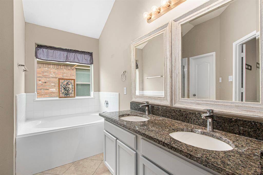Double sinks, granite countertops and updated mirrors in the light-and-bright primary bath.