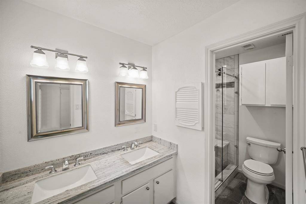 The primary bath features dual vanities, providing ample personal space along with an abundance of custom cabinetry for seamless organization, along with the oversized walk-in shower with beautiful tile work and glass front.