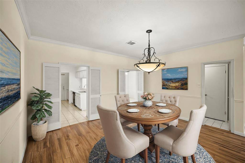 The dining area, nestled within the open-concept layout, features a charming chandelier that adds a touch of elegance and creates the perfect setting for gatherings and meals. - virtually staged