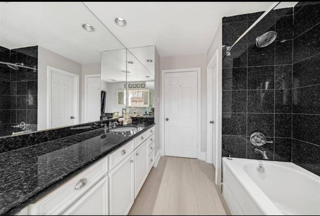 Second full bathroom, also with black granite countertops, offering ample space for daily routine.
