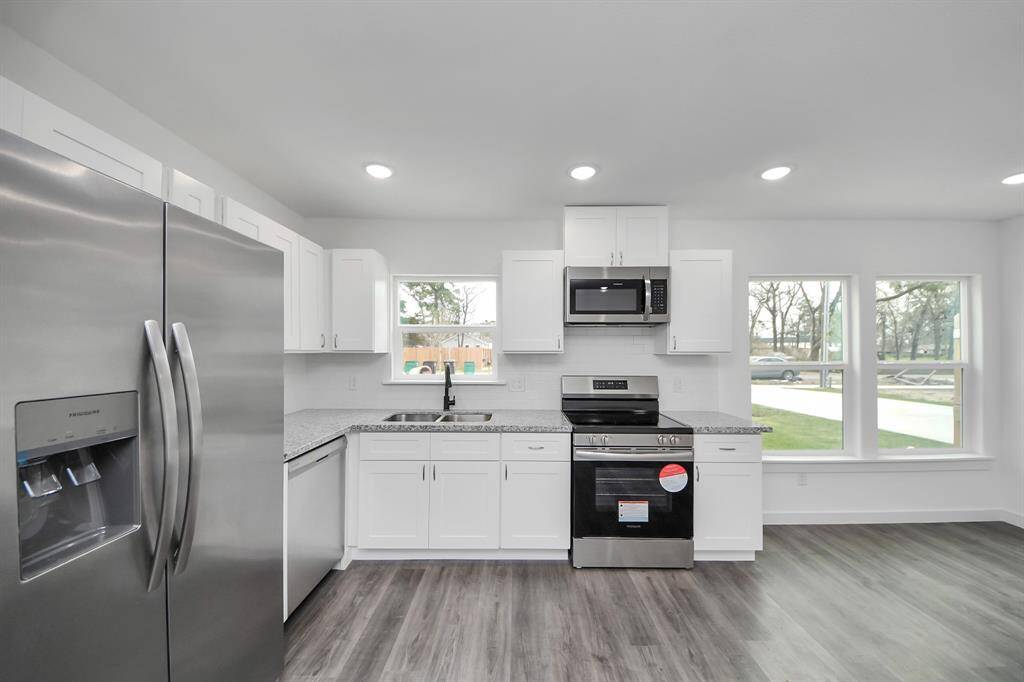 The kitchen features stainless steel appliances, white cabinets, and tile backsplash.