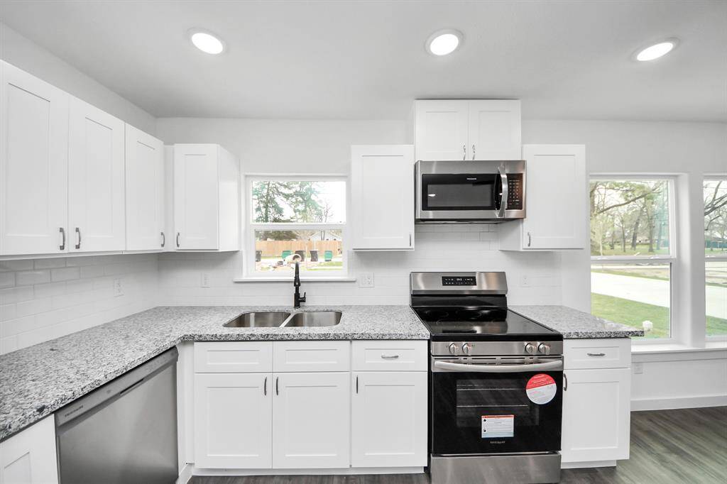 The kitchen features stainless steel appliances, white cabinets, and tile backsplash.