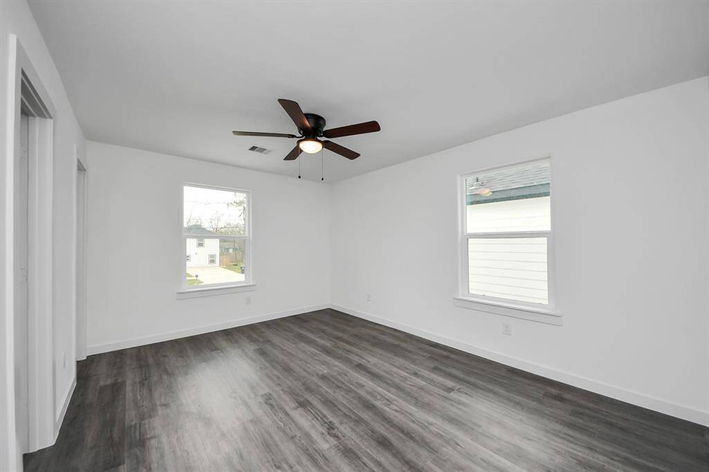 The primary bedroom features a ceiling fan and large windows.