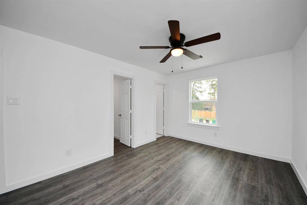 The primary bedroom features a ceiling fan and large windows.