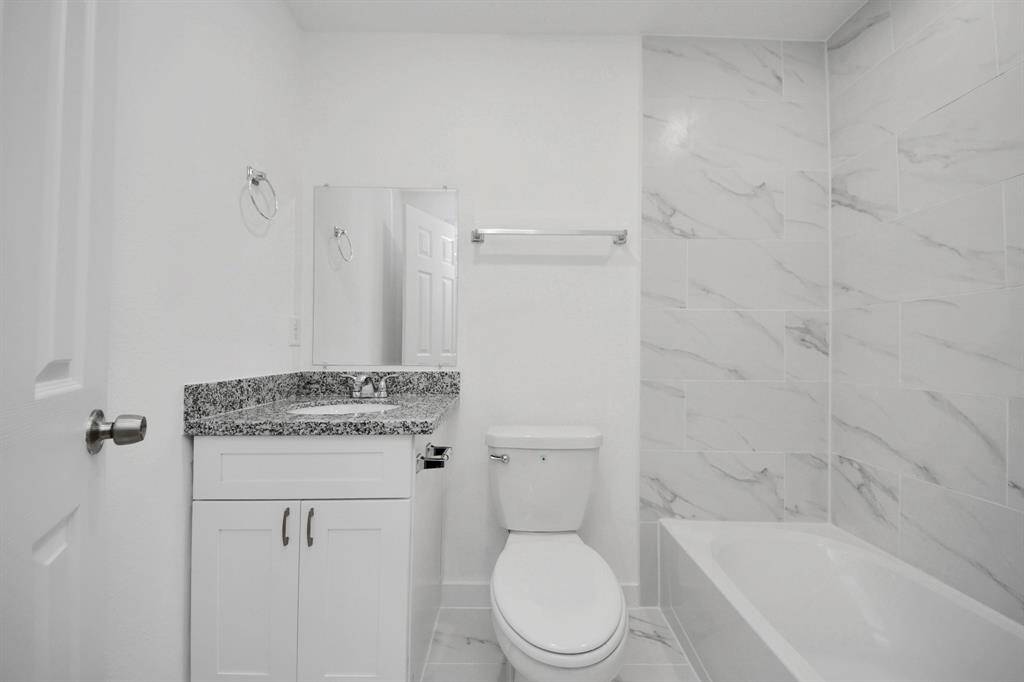 Secondary bathroom features a tub and shower combo with tile surround.