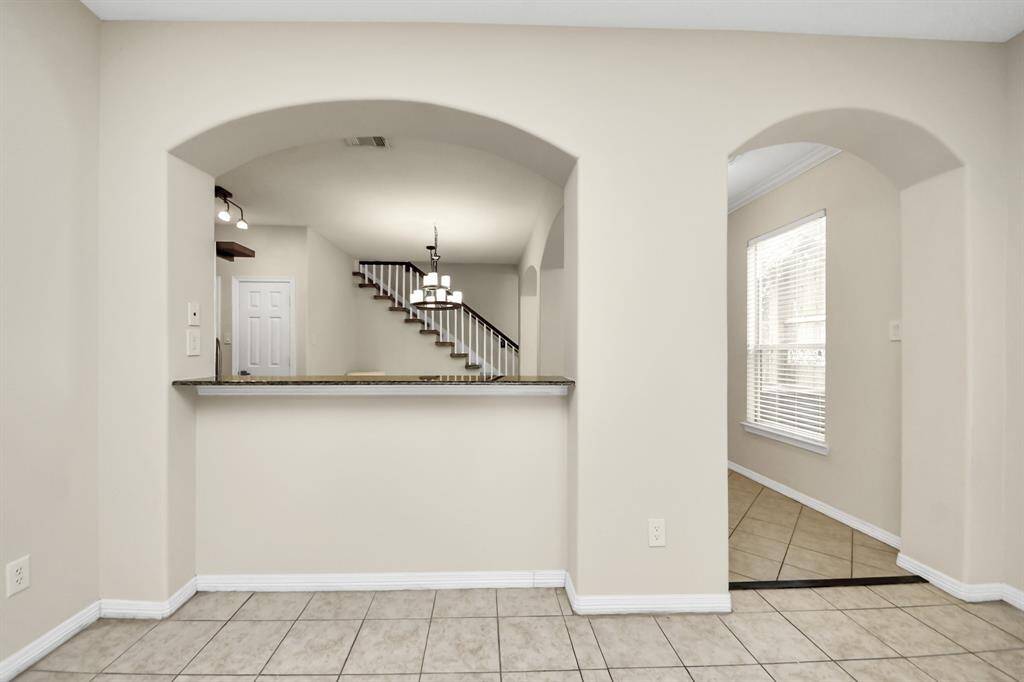 This home features a spacious open layout with tiled floors, neutral walls, and archways that add elegance. The view includes a staircase and abundant natural light from a large window. Ideal for comfortable living and entertaining.
