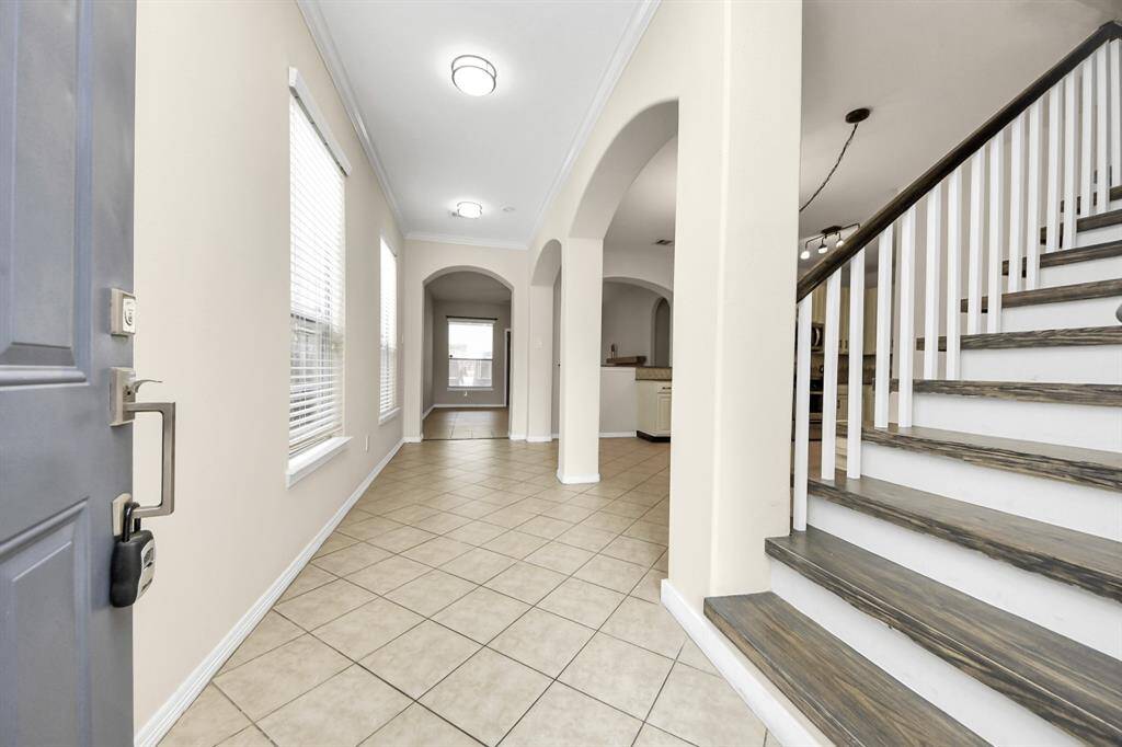 Bright entryway with tiled flooring, neutral walls, and recessed lighting.