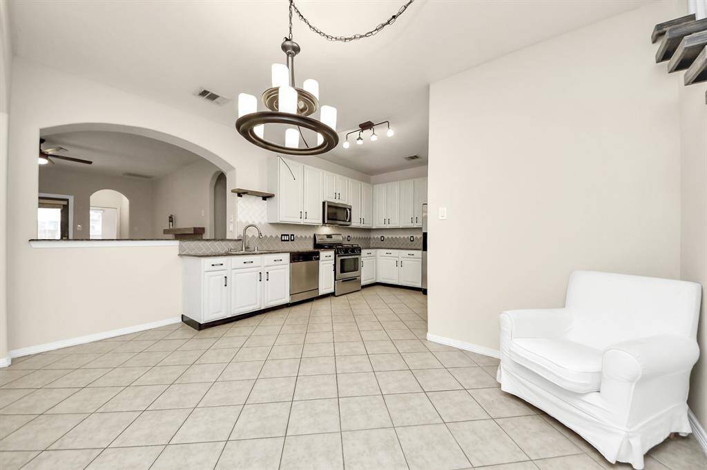 An open layout connects to a cozy living area, enhanced by a chic chandelier and tiled flooring. Perfect for entertaining and everyday living.