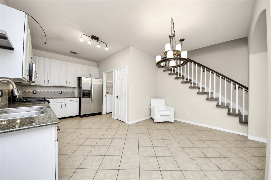 The space features tile flooring, a modern light fixture, and a staircase leading to the upper level, enhancing the room's charm and functionality.