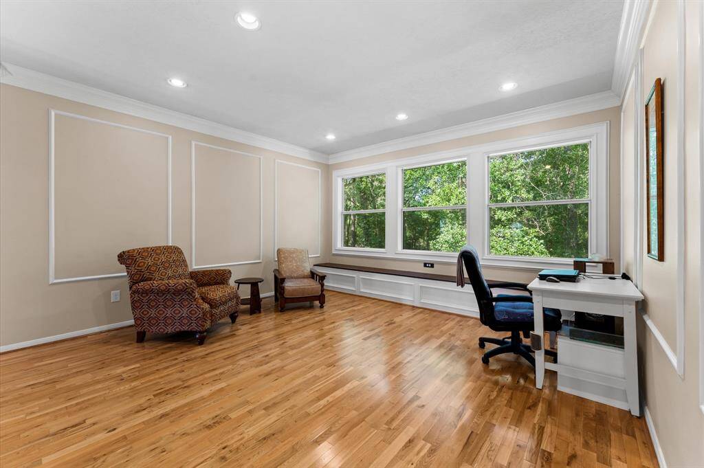 Elegant second gameroom featuring hardwood floors and custom window seats with built-in storage and relaxing wooded views.