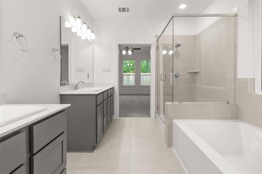 The primary bathroom offers a split double vanity, separate his-and-hers spaces, each with its own sink, mirror, and plenty of counter room for daily routines.