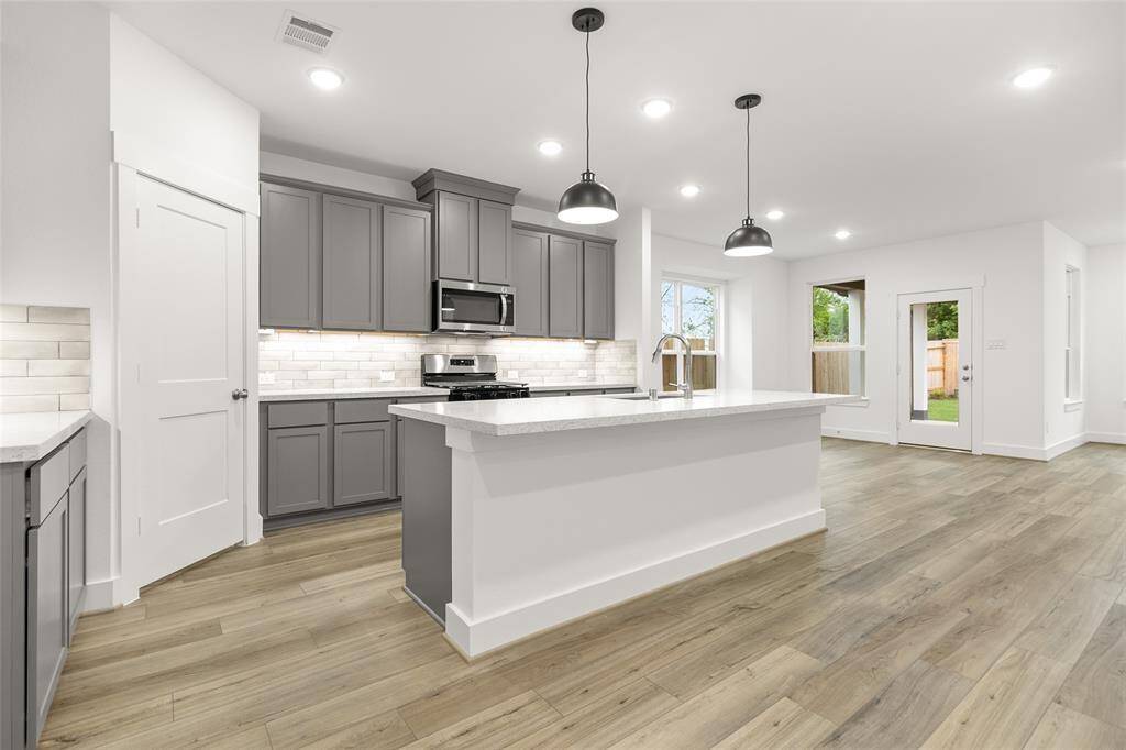 The open concept kitchen is bathed in natural light, highlighting the sleek gray cabinets that lend a modern, sophisticated feel to the space.