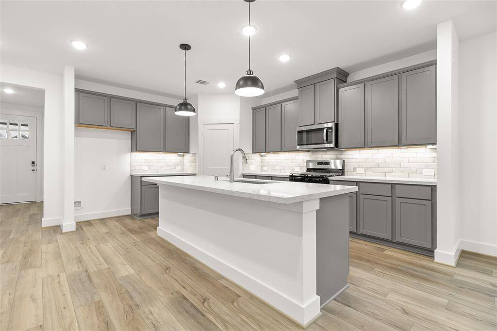A pristine white quartz countertop stretches across the large island and surrounding surfaces, offering both elegance and durability.