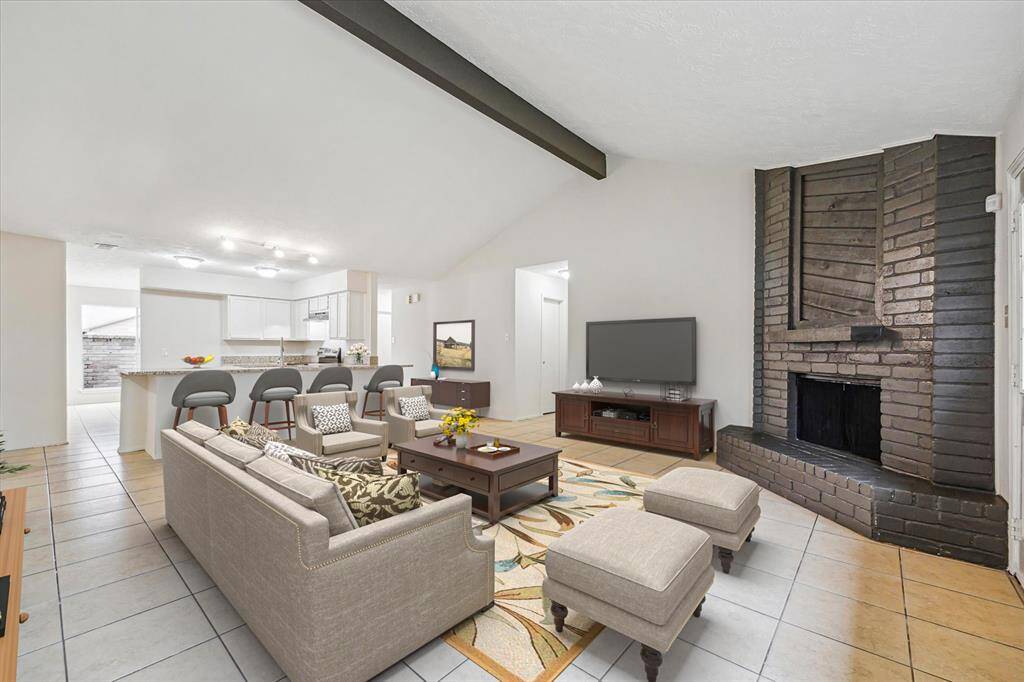 Virtually staged family room. Stately gas fireplace with wood ceiling beam