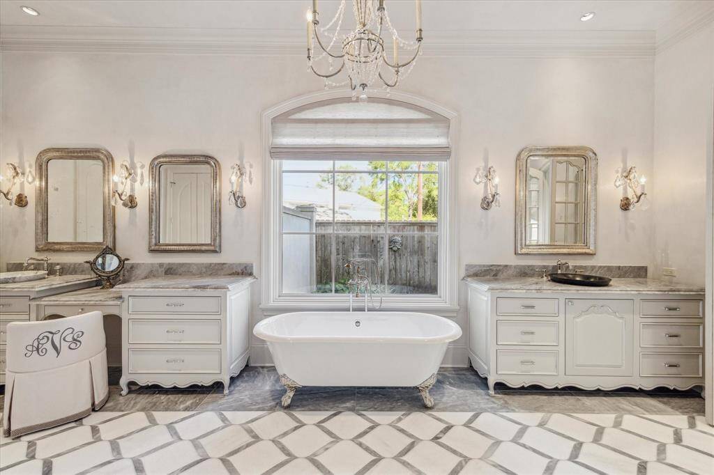 The primary bath includes inlaid marble floor, clawfoot tub, steam shower, two sinks, vanity area and beautiful lighting.