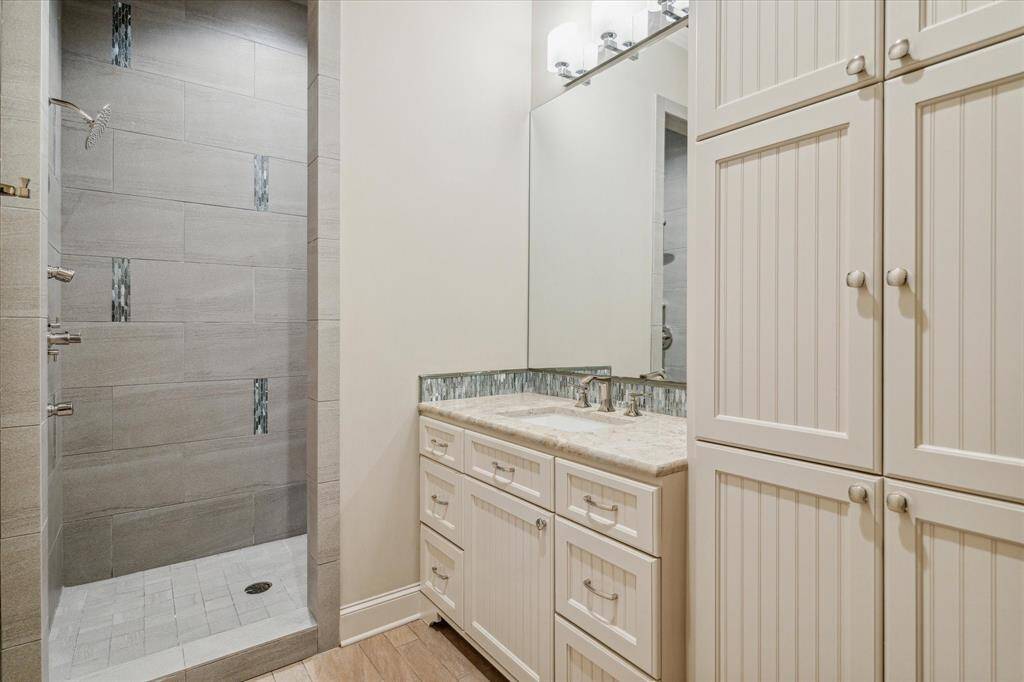 Secondary bath with stone countertop and shower with multiple sprays.