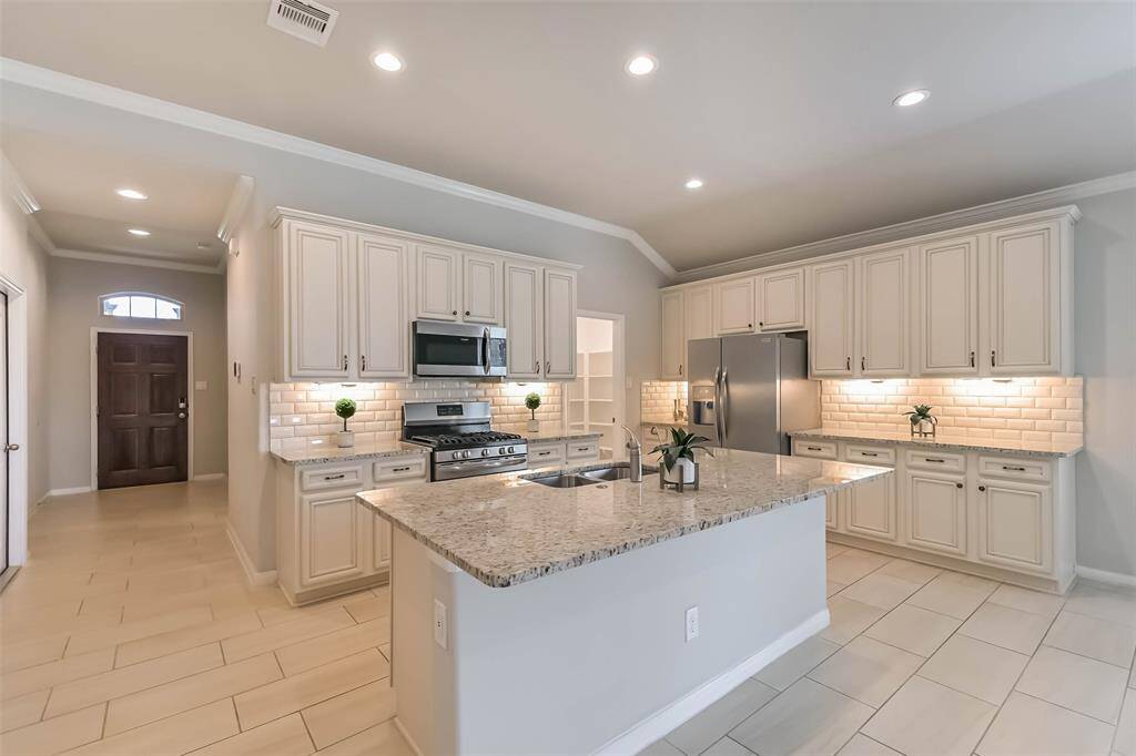 Island kitchen with under cabinet lighting and crown molding.