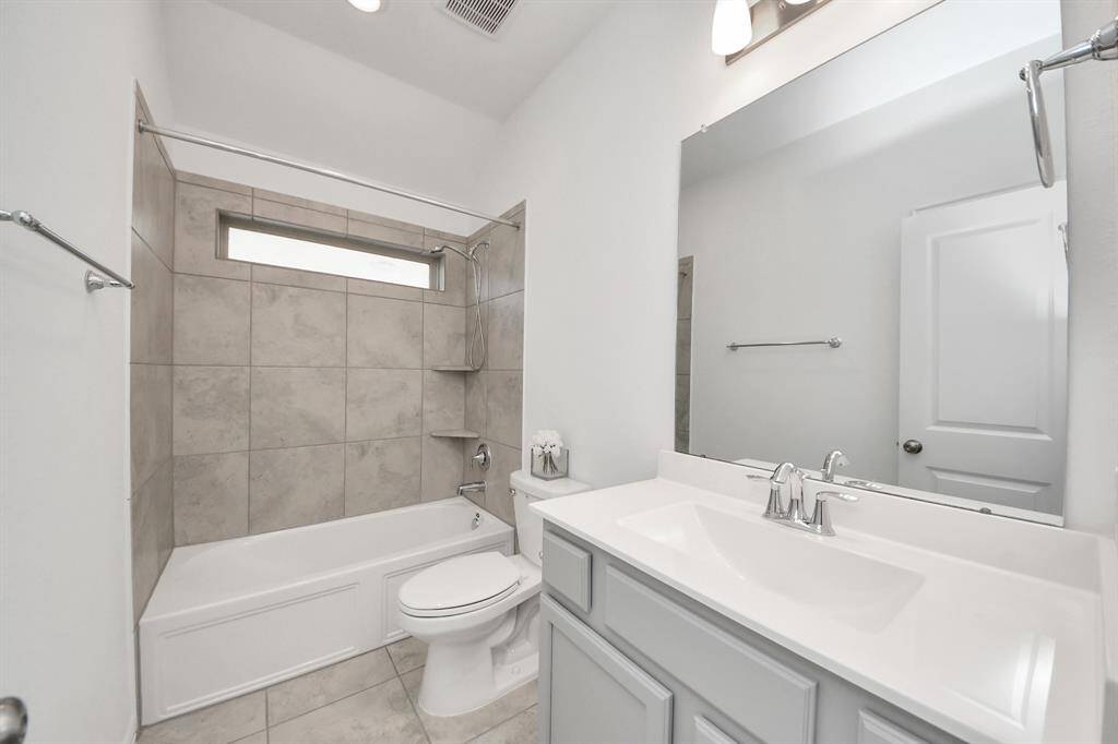 Modern bathroom featuring sleek tilework, a spacious vanity, and a large mirror for a bright, inviting atmosphere.