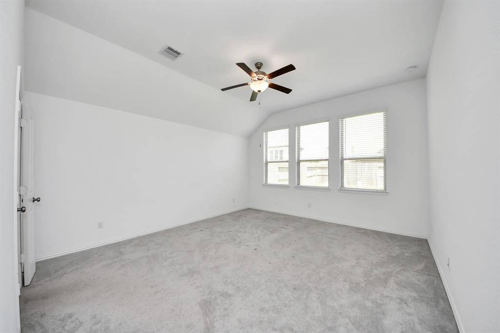 Spacious primary bedroom featuring abundant natural light and a modern ceiling fan for added comfort.