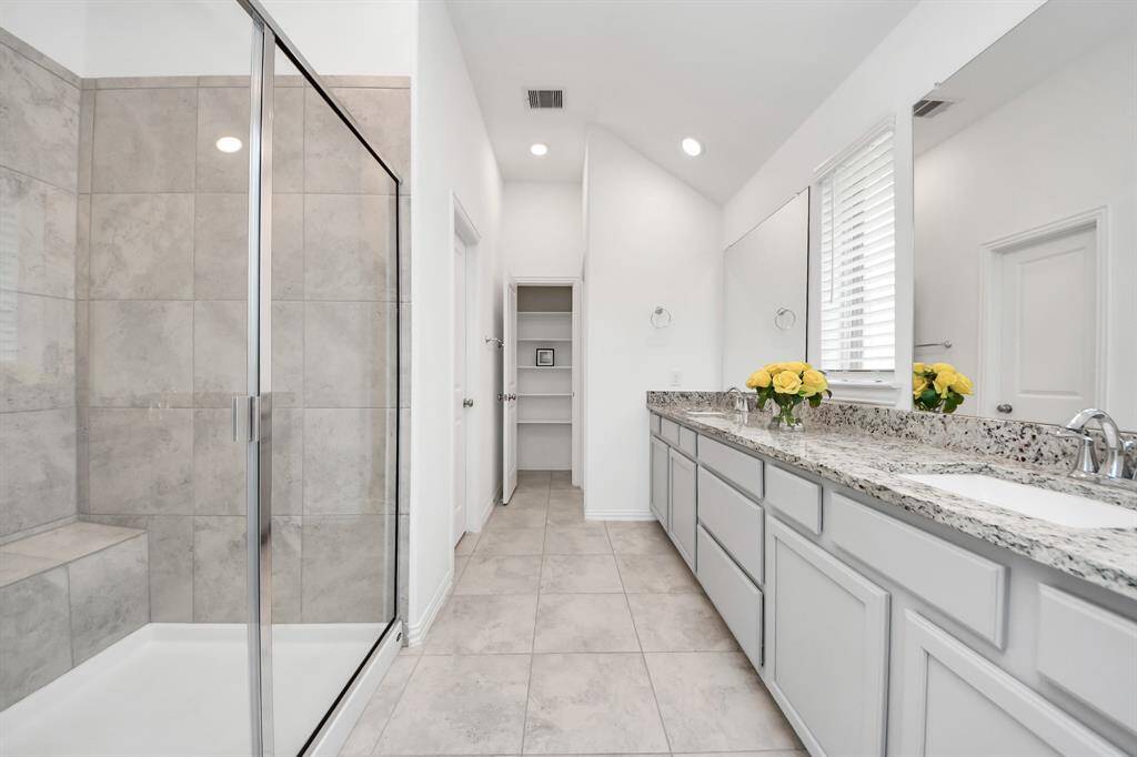 Luxurious en-suite featuring a spacious walk-in shower, elegant dual vanity with granite countertops, and abundant natural light.