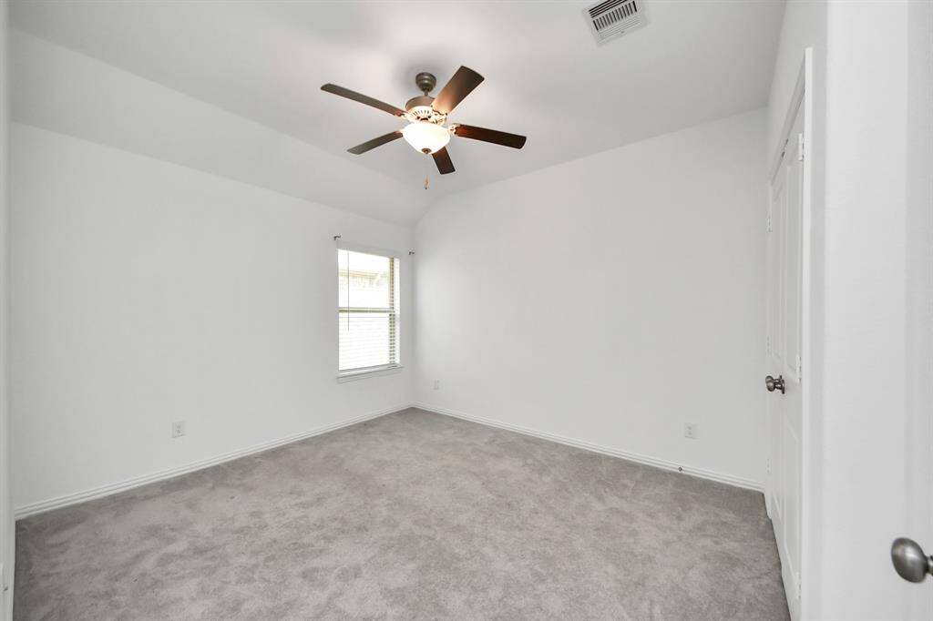 Cozy and bright bedroom with plush carpeting, a stylish ceiling fan, and ample natural light.