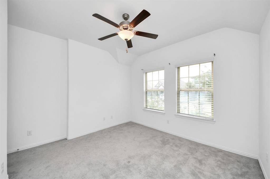 Bright and inviting bedroom featuring large windows for natural light, complemented by a ceiling fan for comfort.