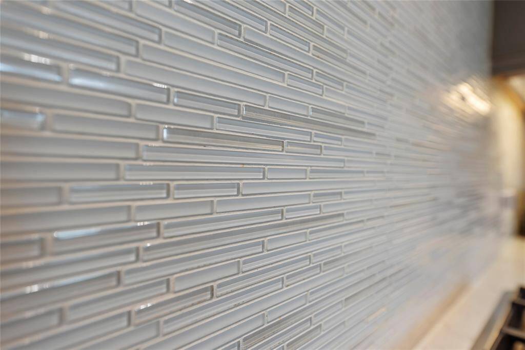 A designer glass tile backsplash adds a touch of modern sophistication, perfectly complementing the surrounding finishes with its sleek, reflective charm.