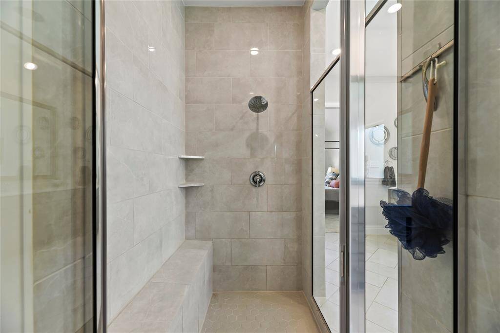 The expansive walk-in shower, adorned with stunning tile work and a sleek glass front, offers a luxurious escape for a quick rinse or a refreshing retreat.