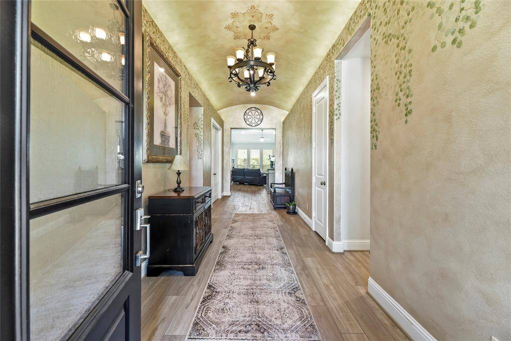Upon entry, the foyer welcomes you with rich vinyl wood plank flooring and soaring arched ceilings crowned by a stunning chandelier. The painted walls and ceiling add a dreamy, elegant touch, setting the tone for the rest of the home.