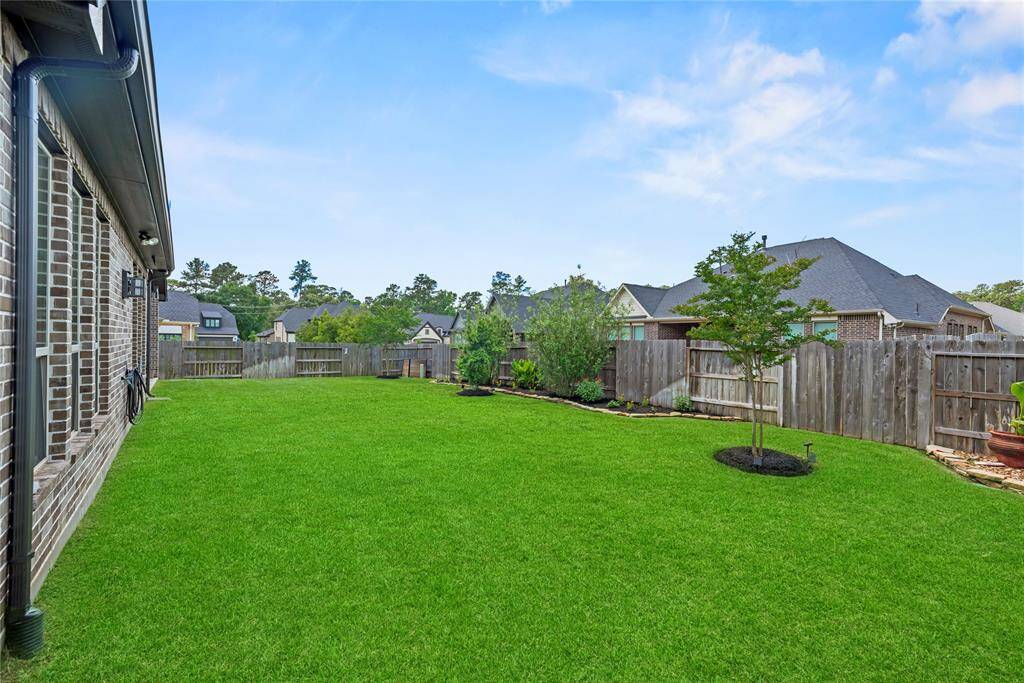 The beautifully landscaped yard offers plenty of lush green space, creating an ideal setting for backyard BBQs and outdoor gatherings.