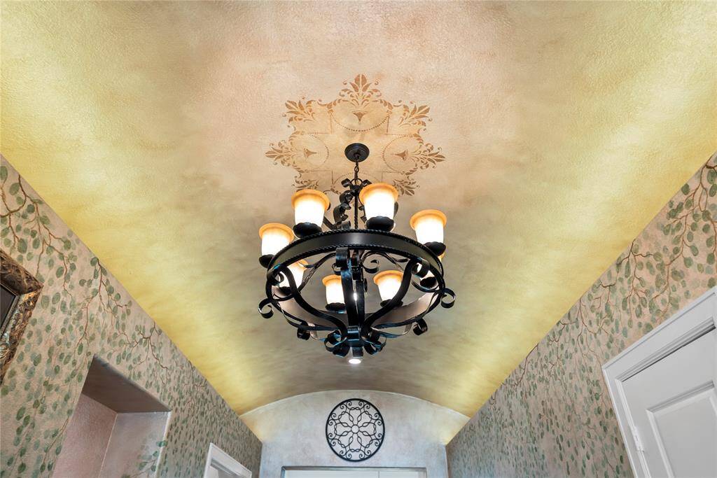 The entryway is crowned by a stunning chandelier that glows beneath a beautifully hand-painted ceiling, creating a breathtaking focal point that exudes elegance and artistry.