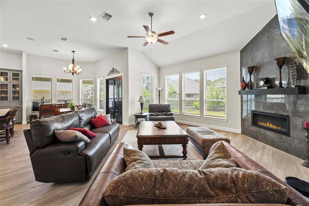 Step into the expansive living space, where an abundance of natural light pours in through large windows, illuminating the open-concept design that seamlessly connects the kitchen and dining areas. A striking slate corner fireplace adds warmth and a touch of modern elegance to this inviting gathering space.